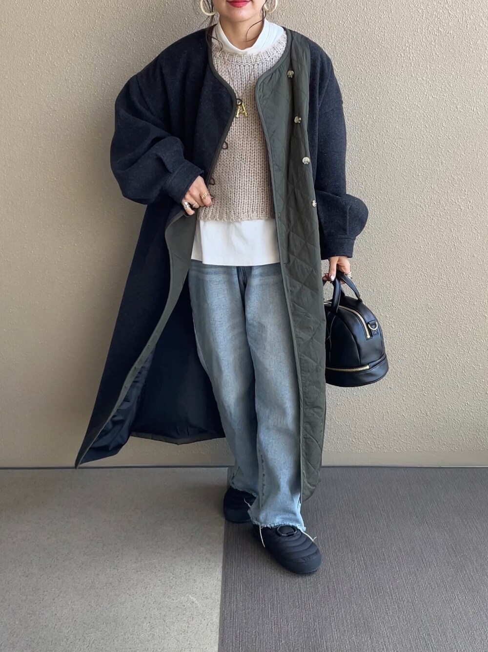 ベージュ系のニット/セーター、グレー系のノーカラーコート、ブラック系のショルダーバッグを着用したレディースの冬コーディネートの1枚目の写真