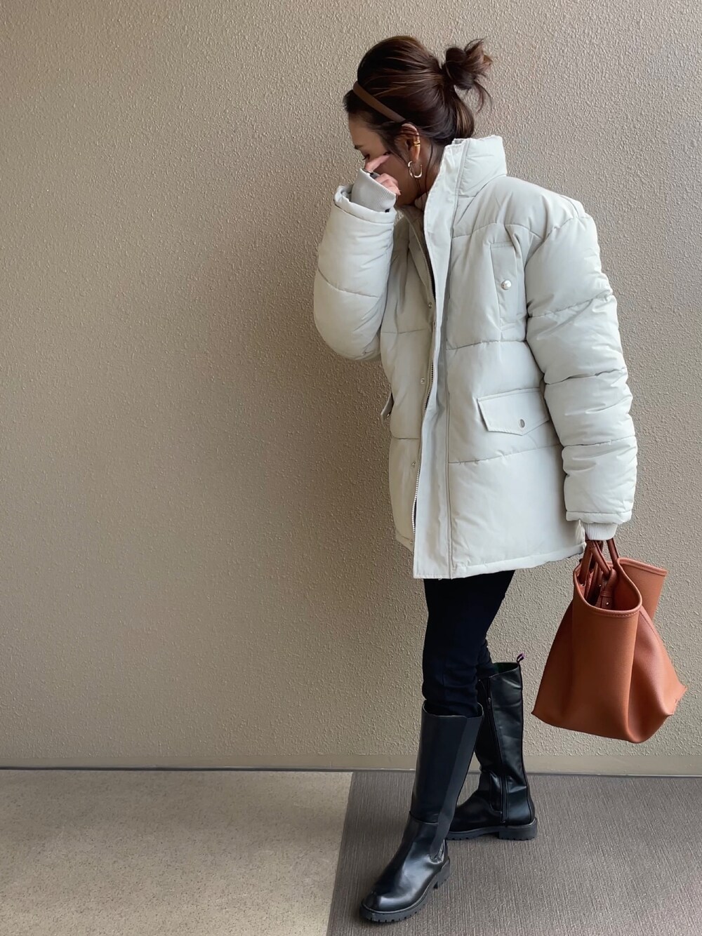ホワイト系のダウンジャケット/コート、ブラック系のブーツ、ブラウン系のバッグを着用したレディースの冬コーディネートの1枚目の写真