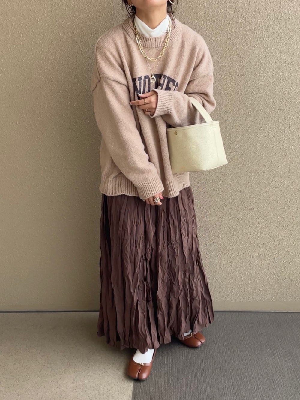 ベージュ系のニット/セーター、ブラウン系のスカート、ブラウン系のパンプスを着用したレディースの冬コーディネートの1枚目の写真