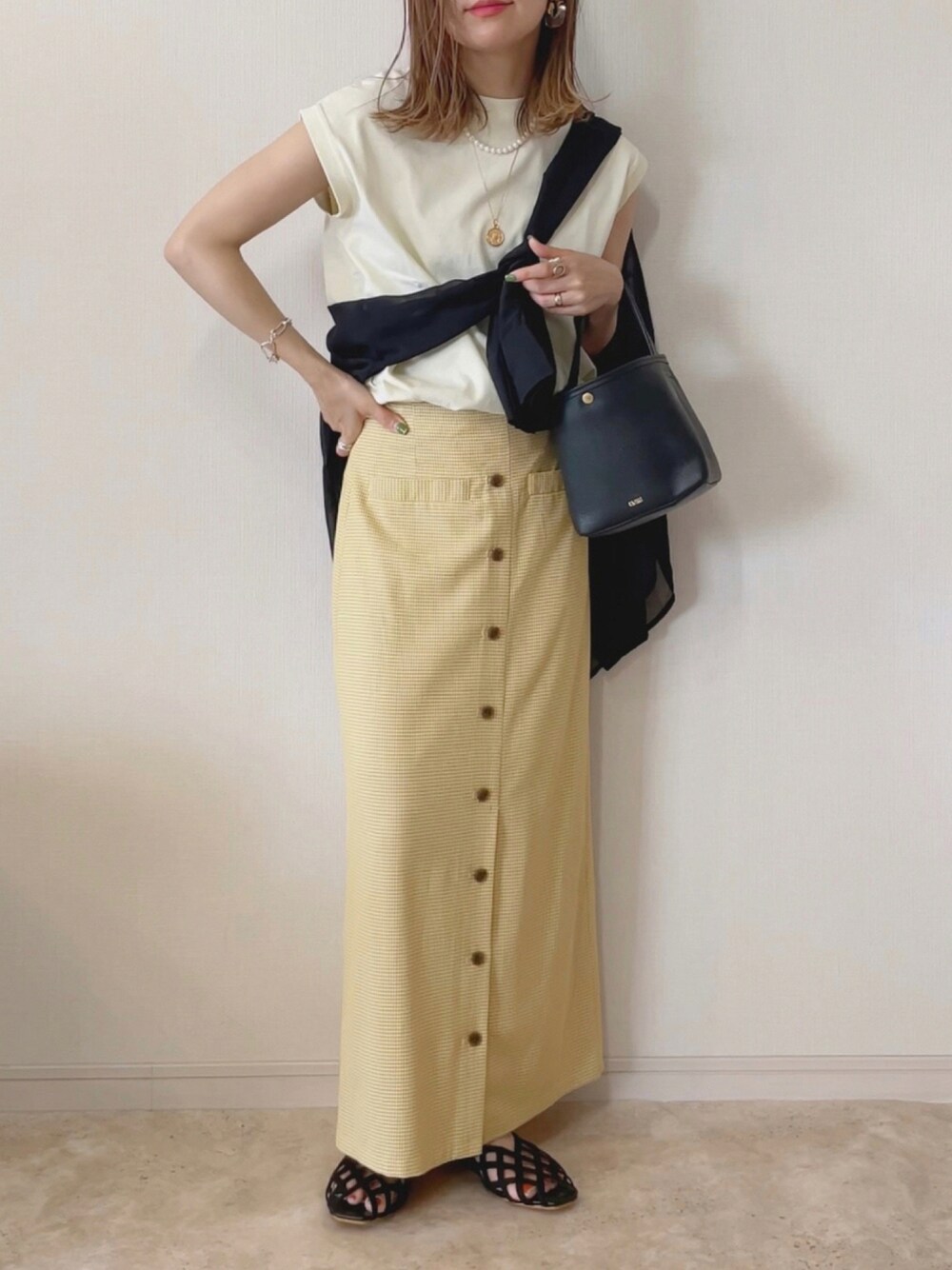 ベージュ系のTシャツ/カットソー、イエロー系のスカート、ブラック系のTシャツ/カットソーを着用したレディースの夏コーディネートの1枚目の写真