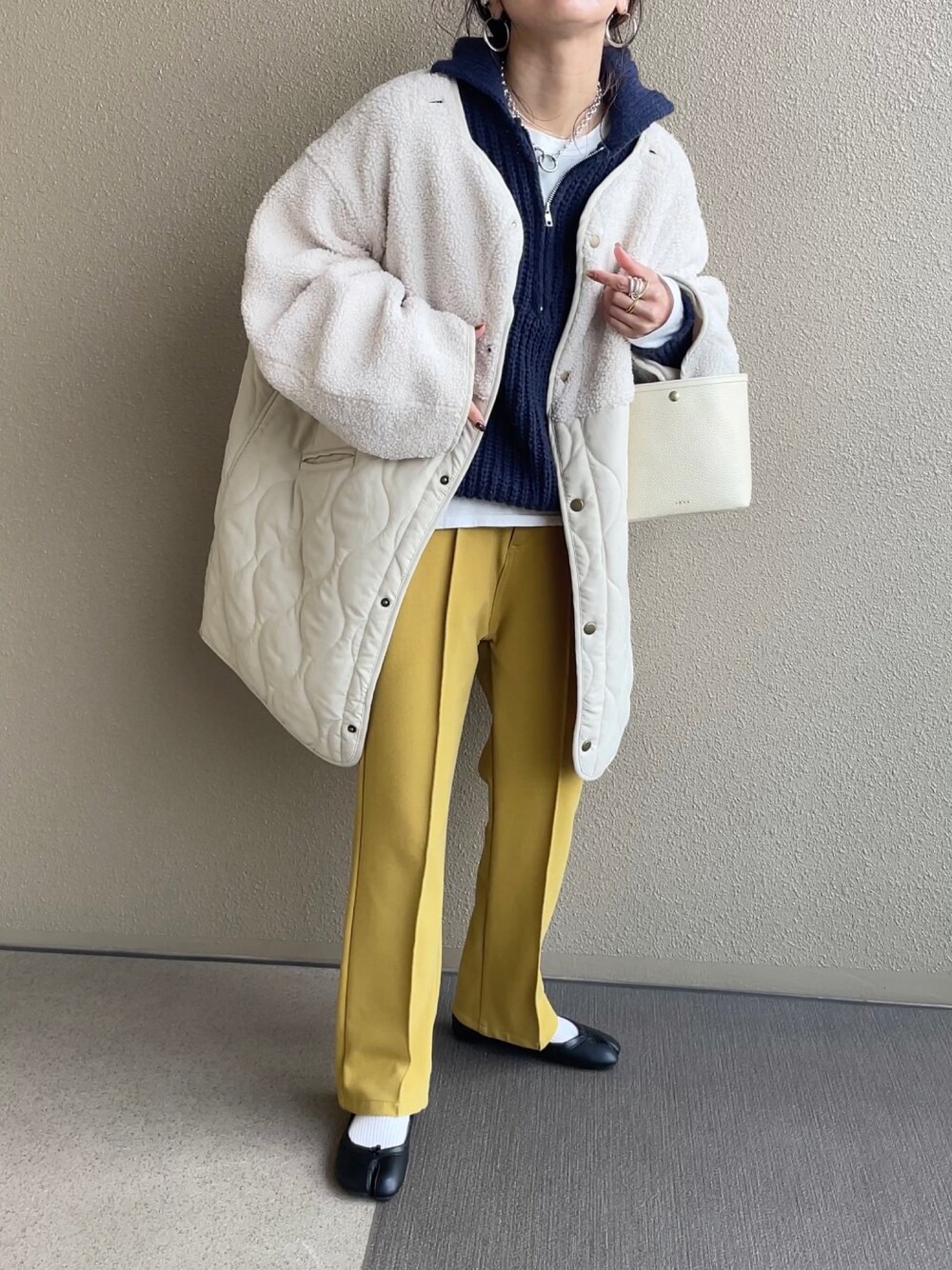 ホワイト系のノーカラージャケット、ブルー系のニット/セーター、イエロー系のその他パンツを着用したレディースの冬コーディネートの1枚目の写真