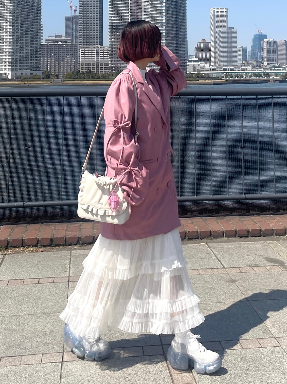 ピンク系のテーラードジャケット、ホワイト系のハンドバッグ、ホワイト系のスニーカーを着用したレディースの春コーディネートの1枚目の写真