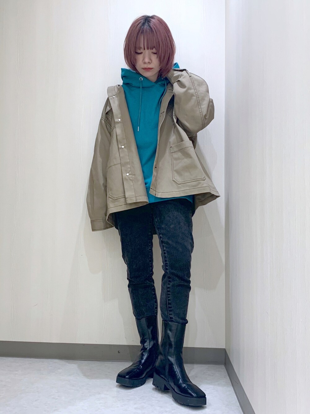 ブラック系のデニムパンツ、ブラック系のブーツ、グリーン系のパーカーを着用したレディースの秋コーディネートの1枚目の写真