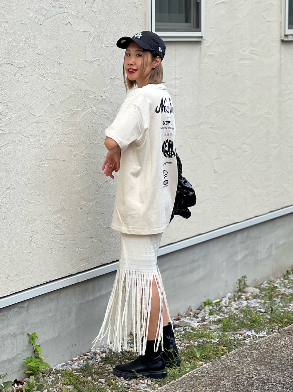 ベージュ系のTシャツ/カットソー、ブラック系のトートバッグ、ホワイト系のスカートを着用したレディースの夏コーディネートの1枚目の写真