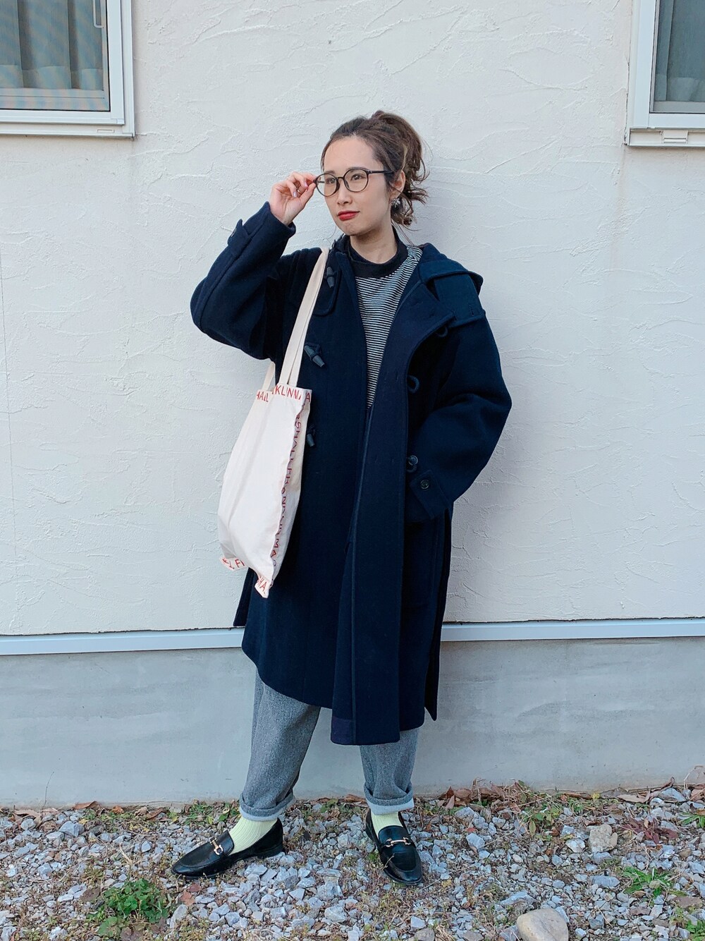 ブラック系のダッフルコート、ブラック系のローファー、レッド系のトートバッグを着用したレディースの冬コーディネートの1枚目の写真