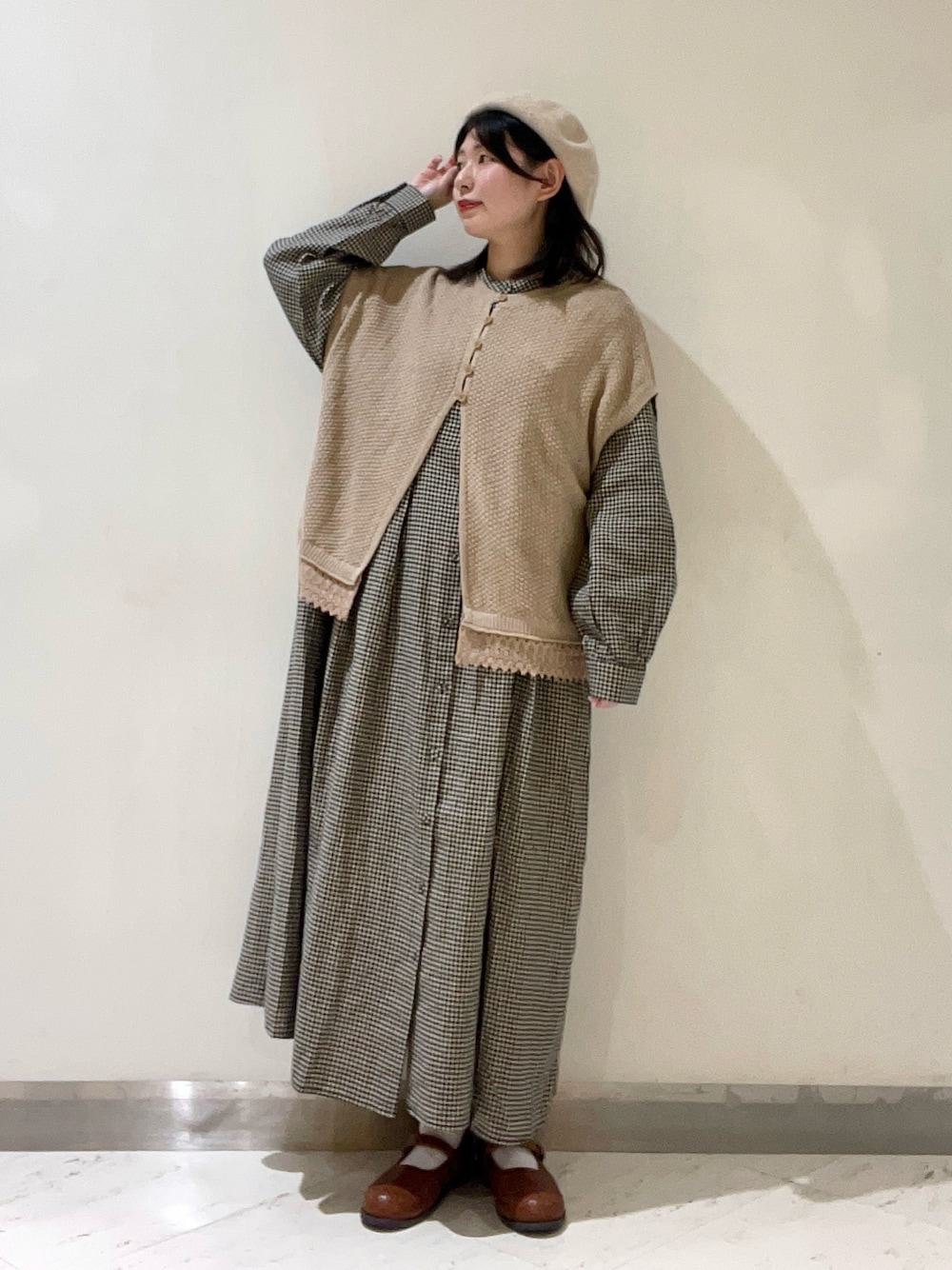 ベージュ系のベスト、イエロー系のドレスシューズ、ベージュ系のワンピースを着用したレディースの冬コーディネートの1枚目の写真