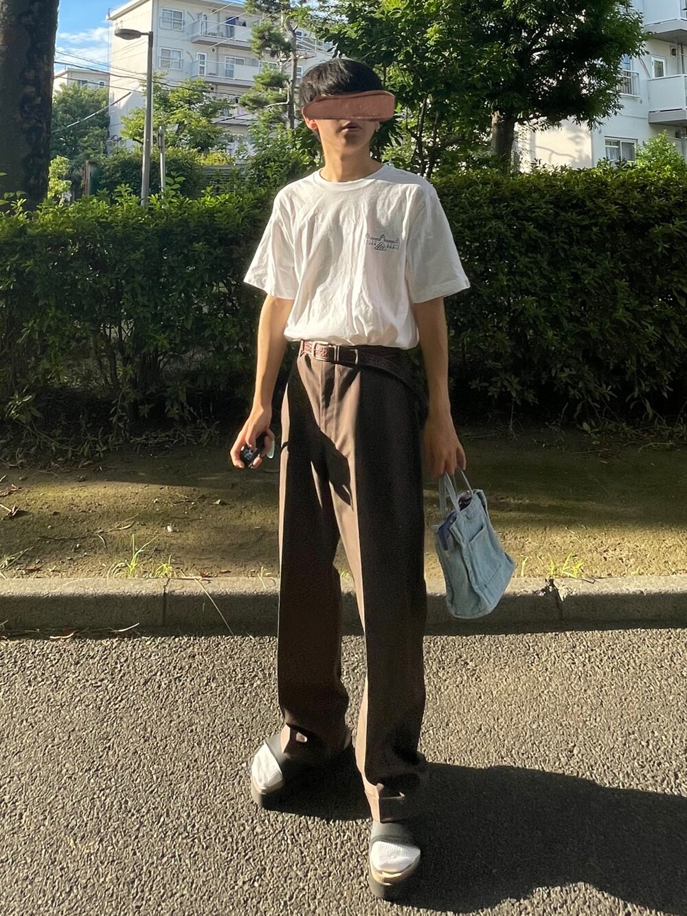 ホワイト系のTシャツ/カットソー、ブラウン系のスラックス、ブルー系のバッグを着用したメンズの夏コーディネートの1枚目の写真
