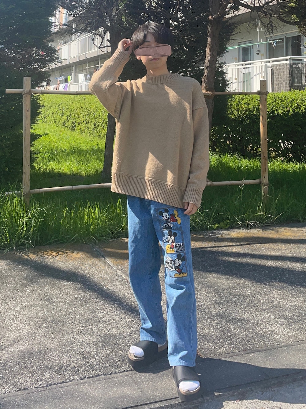 ベージュ系のニット/セーター、ブルー系のデニムパンツ、ブラック系のサンダルを着用したメンズの春コーディネートの1枚目の写真