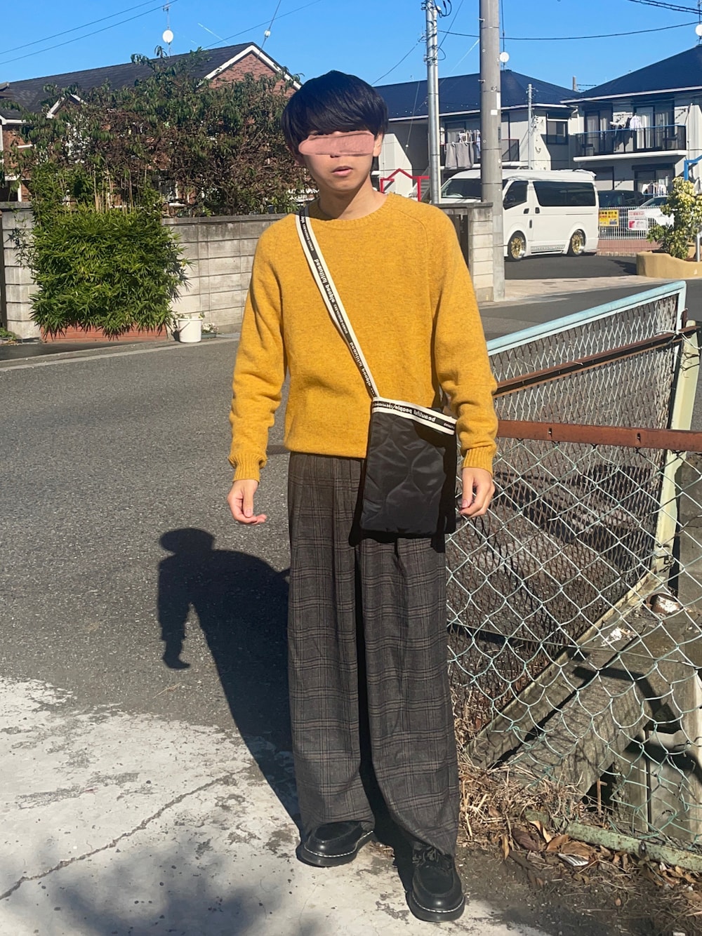 イエロー系のニット/セーター、ブラック系のショルダーバッグ、グレー系のスラックスを着用したメンズの秋コーディネートの1枚目の写真