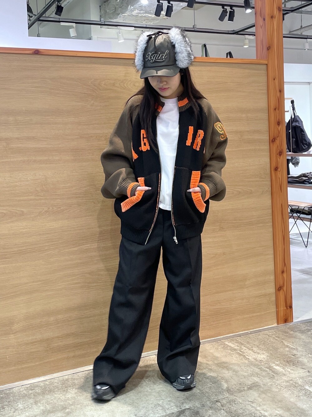 ブラック系のスラックス、ホワイト系のTシャツ/カットソー、ブラウン系のニット/セーターを着用したレディースの秋コーディネートの1枚目の写真