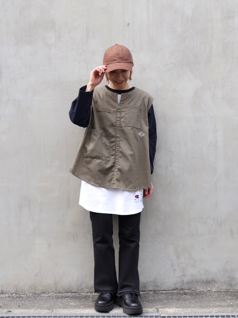 グリーン系のベスト、ホワイト系のTシャツ/カットソー、ブラック系のデニムパンツを着用したレディースの春コーディネートの2枚目の写真