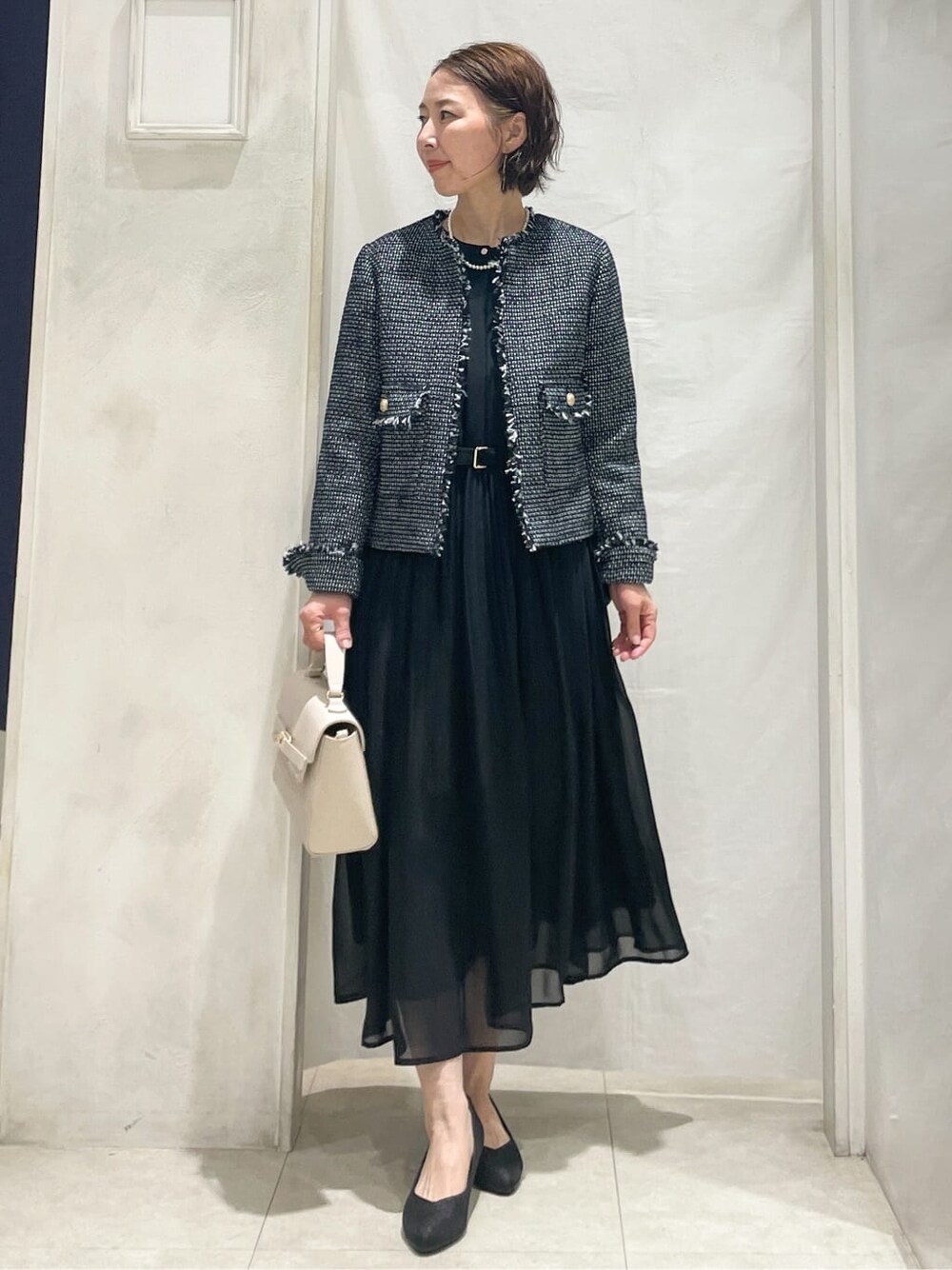 ブルー系のノーカラージャケット、ブラック系のワンピース、ベージュ系のショルダーバッグを着用したレディースの冬コーディネートの1枚目の写真