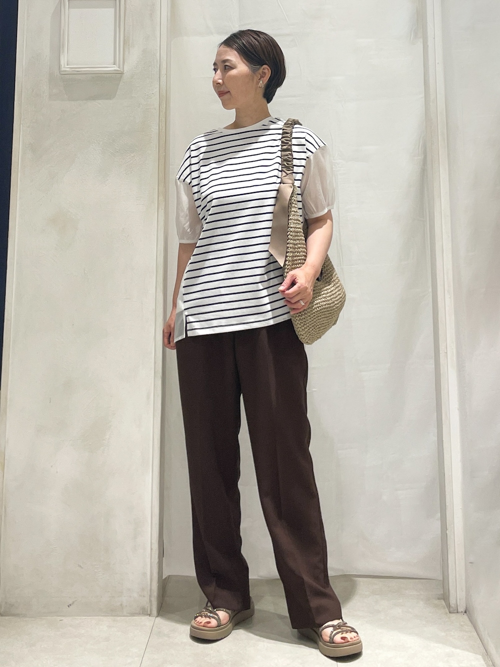 ホワイト系のTシャツ/カットソー、ブラウン系のその他パンツ、ベージュ系のショルダーバッグを着用したレディースの夏コーディネートの1枚目の写真