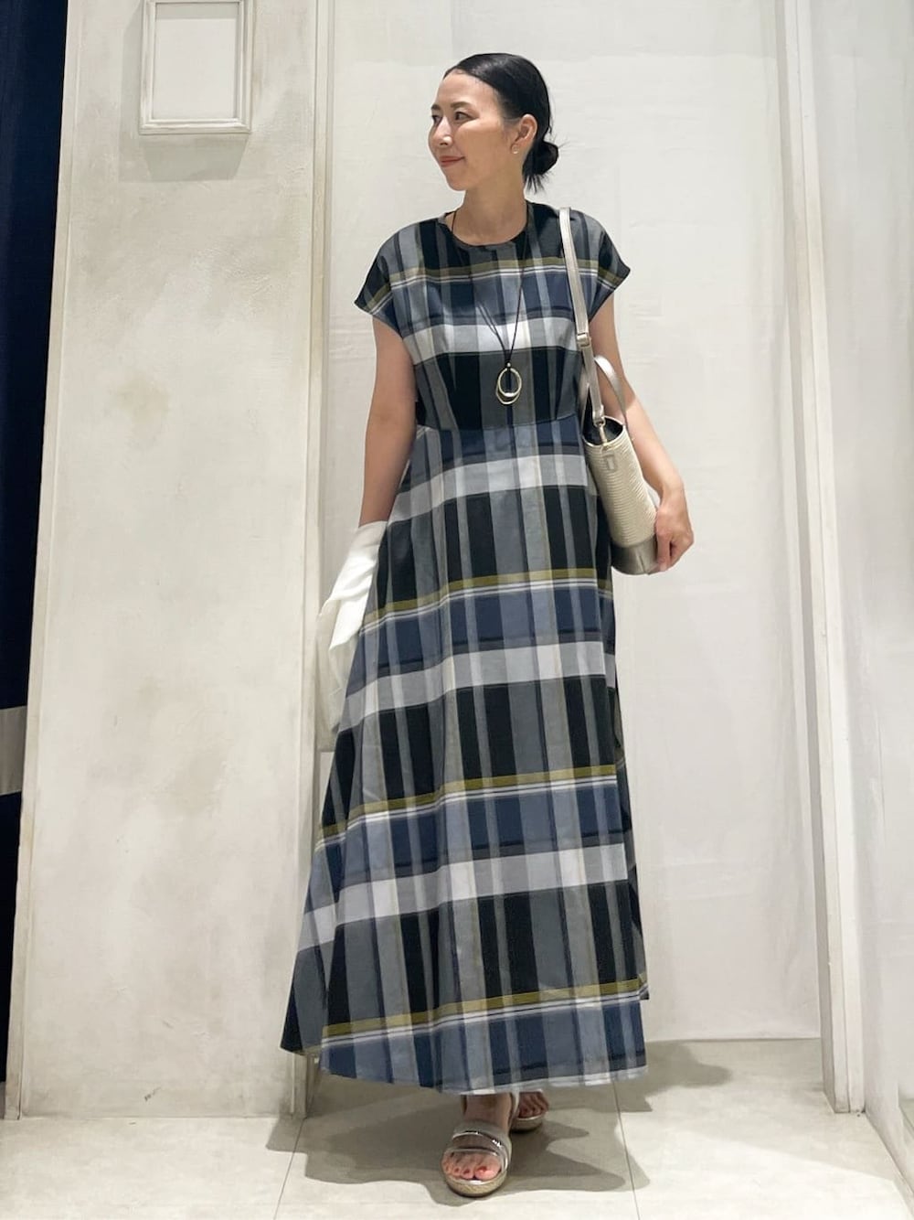 シルバー系のトートバッグ、ゴールド系のイヤリング、ゴールド系のネックレスを着用したレディースの夏コーディネートの1枚目の写真