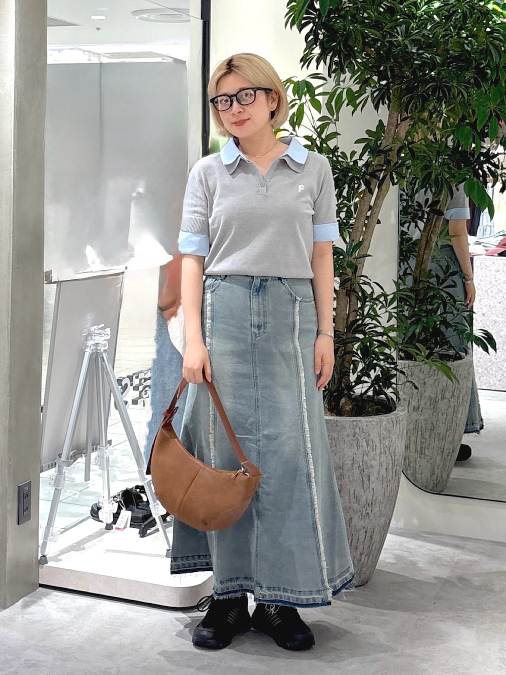グレー系のニット/セーター、ブルー系のスカート、ブラウン系のハンドバッグを着用したレディースの夏コーディネートの1枚目の写真