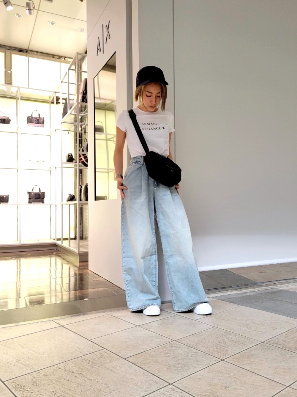 ホワイト系のスニーカー、ホワイト系のTシャツ/カットソー、ブラック系のショルダーバッグを着用したレディースの春コーディネートの1枚目の写真