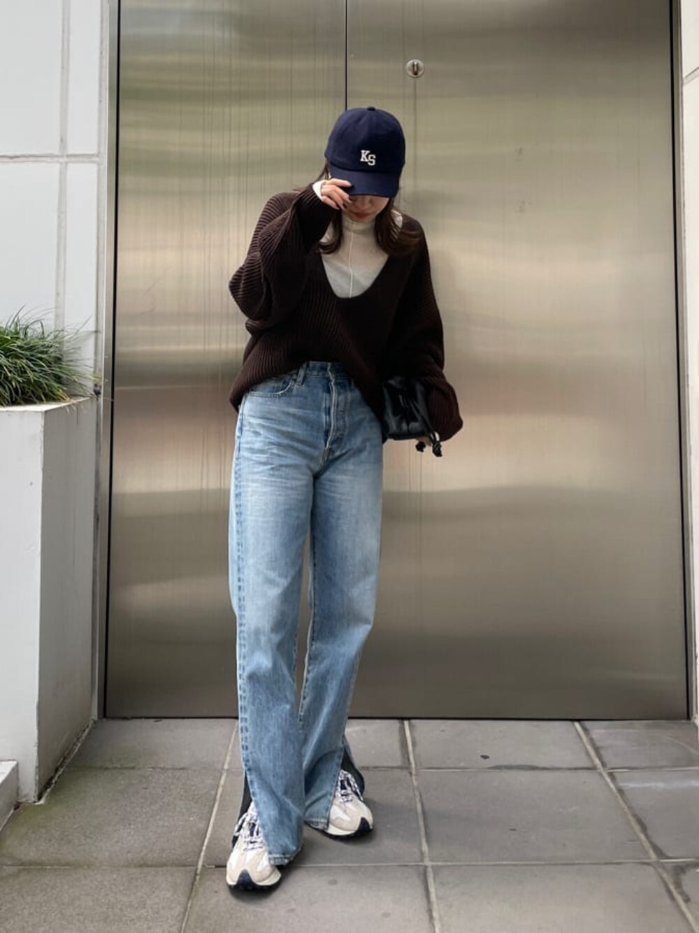 ブラック系のクラッチバッグ、ブルー系のデニムパンツ、ブルー系のデニムパンツを着用したレディースの秋コーディネートの1枚目の写真