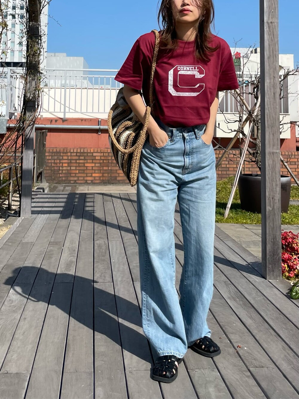 ベージュ系のトートバッグ、ブラック系のサンダル、ブルー系のデニムパンツを着用したレディースの春コーディネートの1枚目の写真