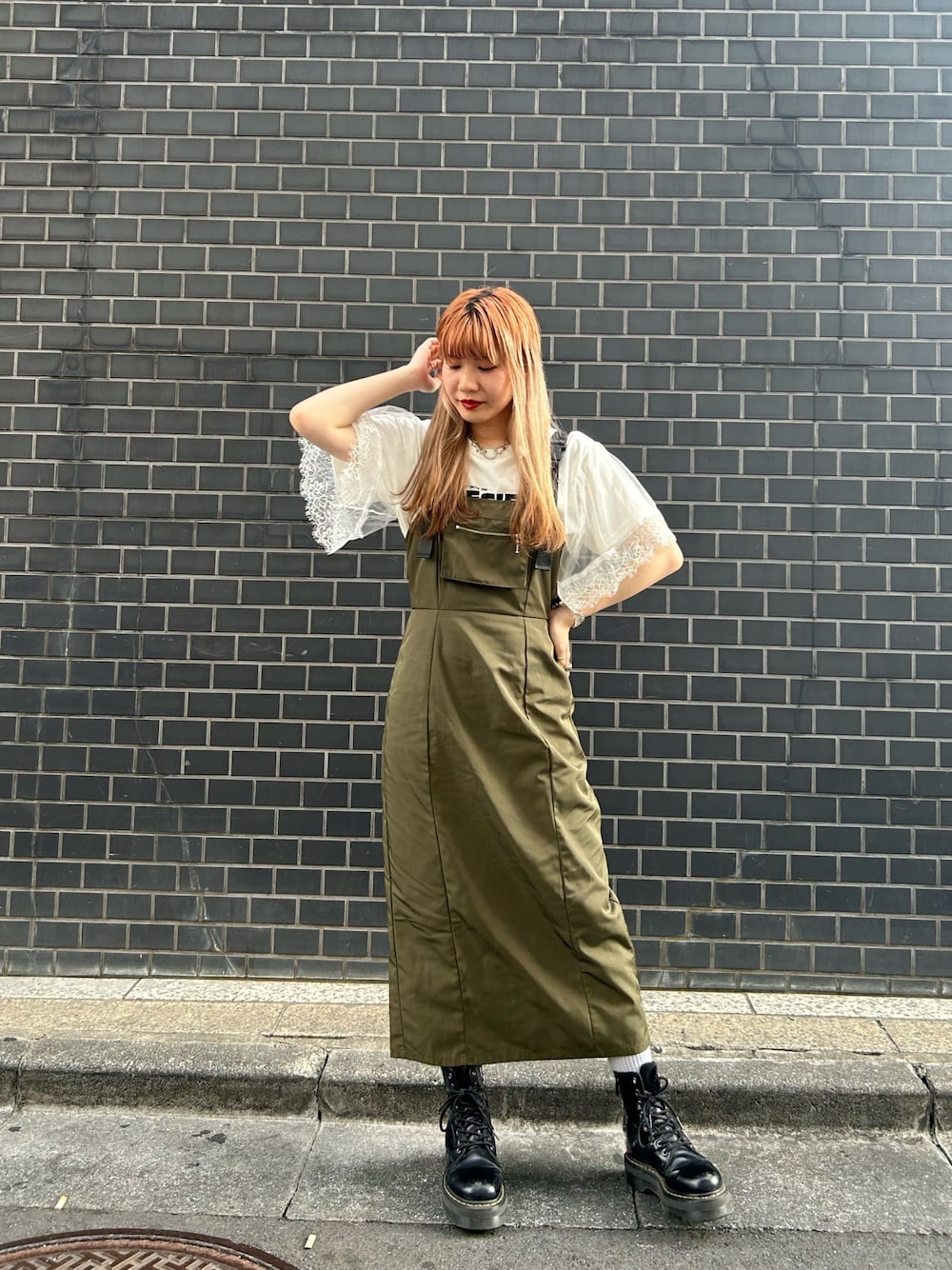 ブラック系のブーツ、グリーン系のジャンパースカート、ホワイト系のTシャツ/カットソーを着用したレディースの夏コーディネートの1枚目の写真