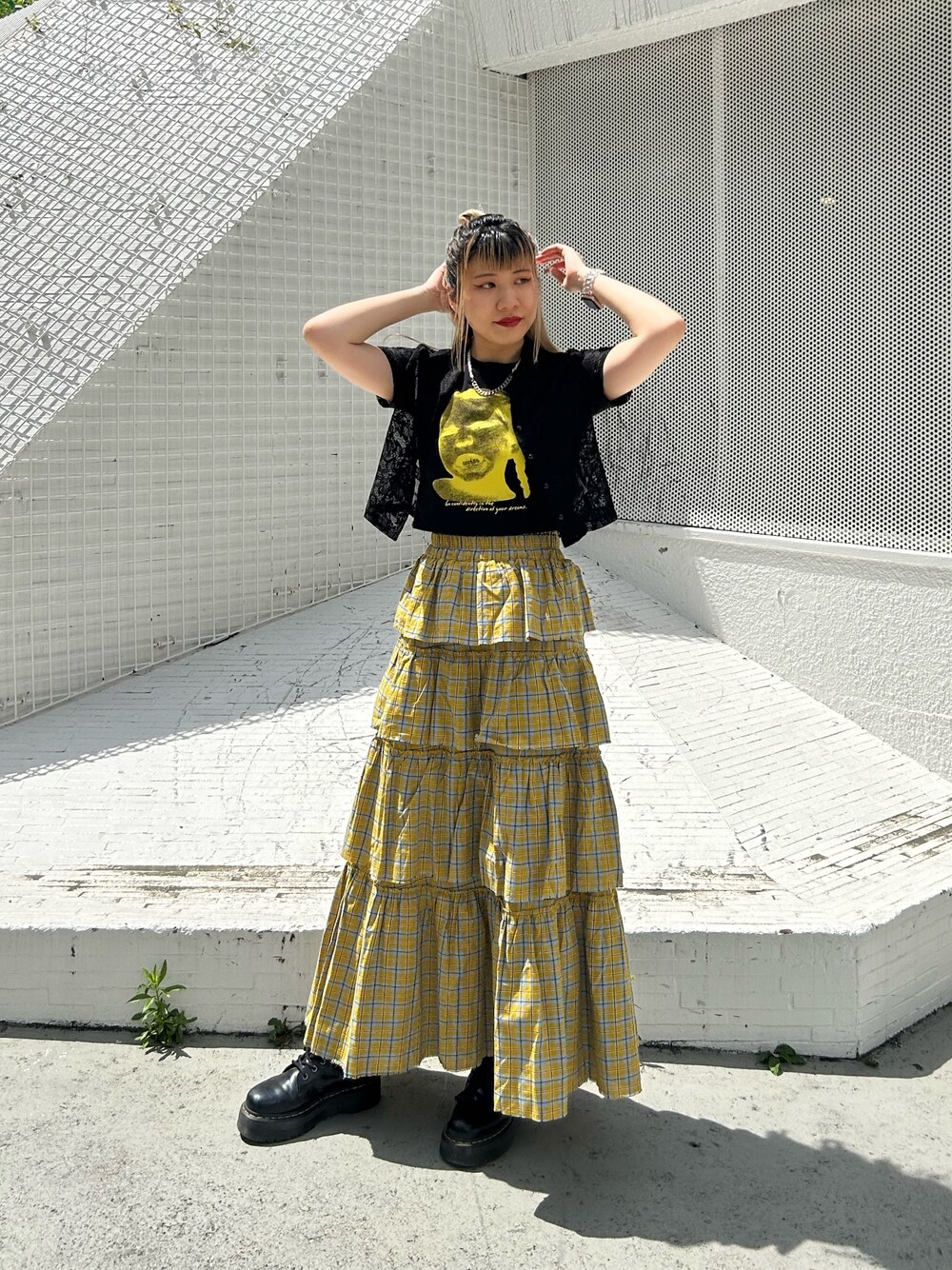 ブラック系のブーツ、イエロー系のスカート、ブラック系のTシャツ/カットソーを着用したレディースの春コーディネートの1枚目の写真