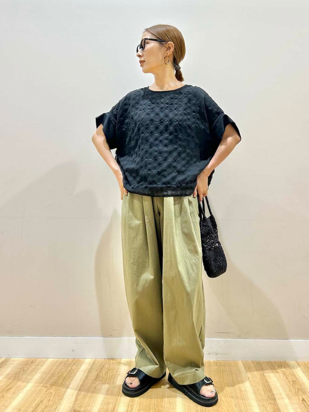 グリーン系のその他パンツ、ブラック系のショルダーバッグ、ブラック系のシャツ/ブラウスを着用したレディースの夏コーディネートの1枚目の写真