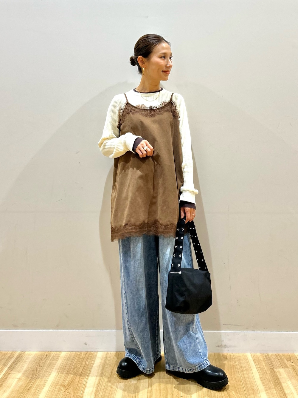 ブルー系のデニムパンツ、ブラック系のショルダーバッグ、ブラック系のブーツを着用したレディースの秋コーディネートの1枚目の写真