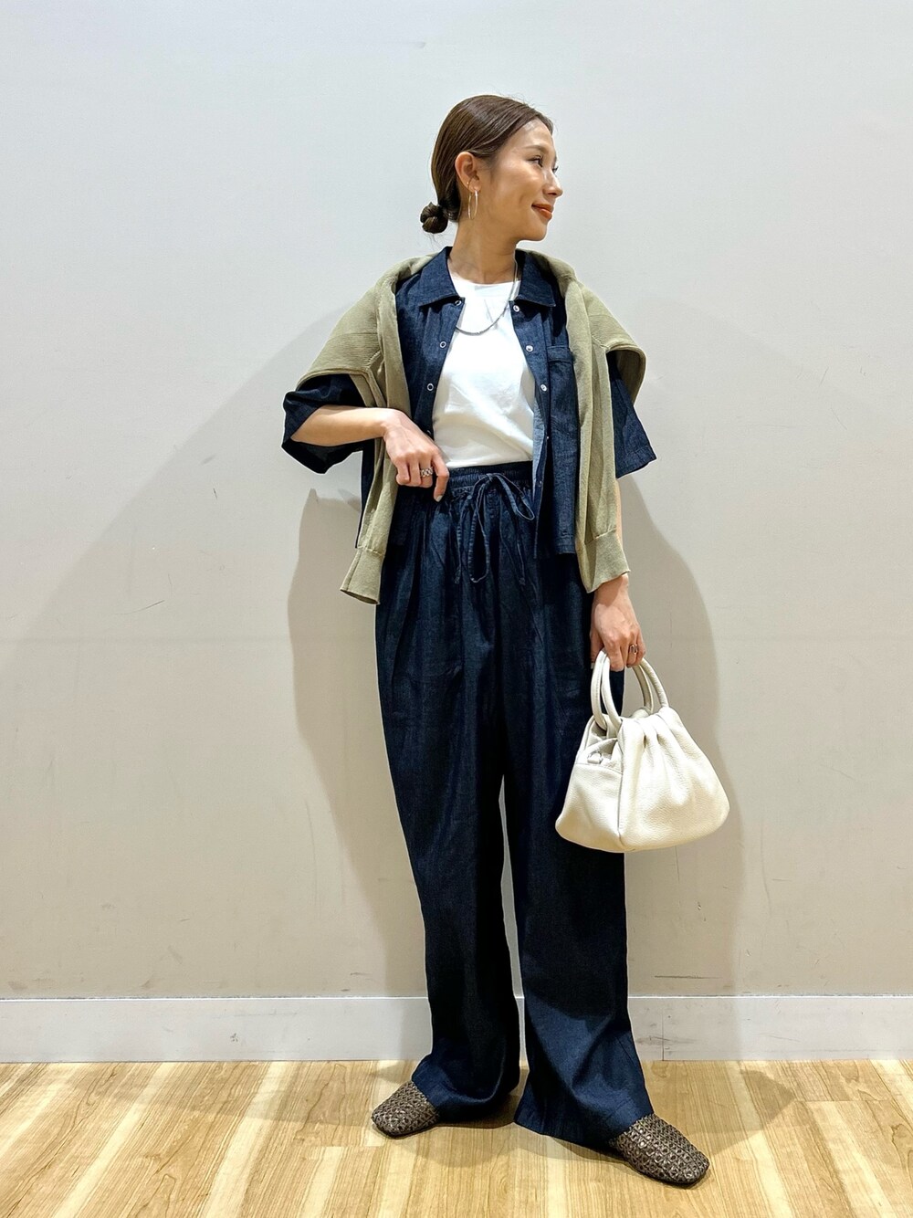 ホワイト系のTシャツ/カットソー、ブルー系のデニムパンツ、ブラウン系のハンドバッグを着用したレディースの春コーディネートの1枚目の写真