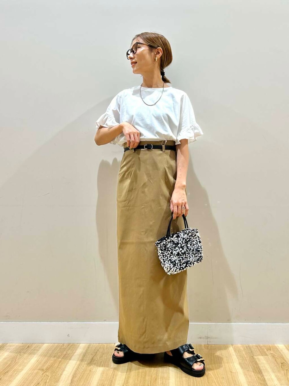 シルバー系のショルダーバッグ、ブラック系のサンダル、ホワイト系のTシャツ/カットソーを着用したレディースの春コーディネートの1枚目の写真