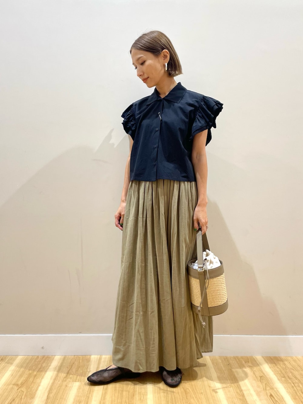 イエロー系のスカート、ブラック系のシャツ/ブラウスを着用したレディースの夏コーディネートの1枚目の写真
