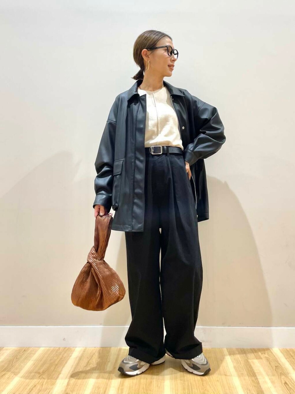 ホワイト系のニット/セーター、ブラウン系のハンドバッグ、ブラック系のその他アウターを着用したレディースの秋コーディネートの1枚目の写真