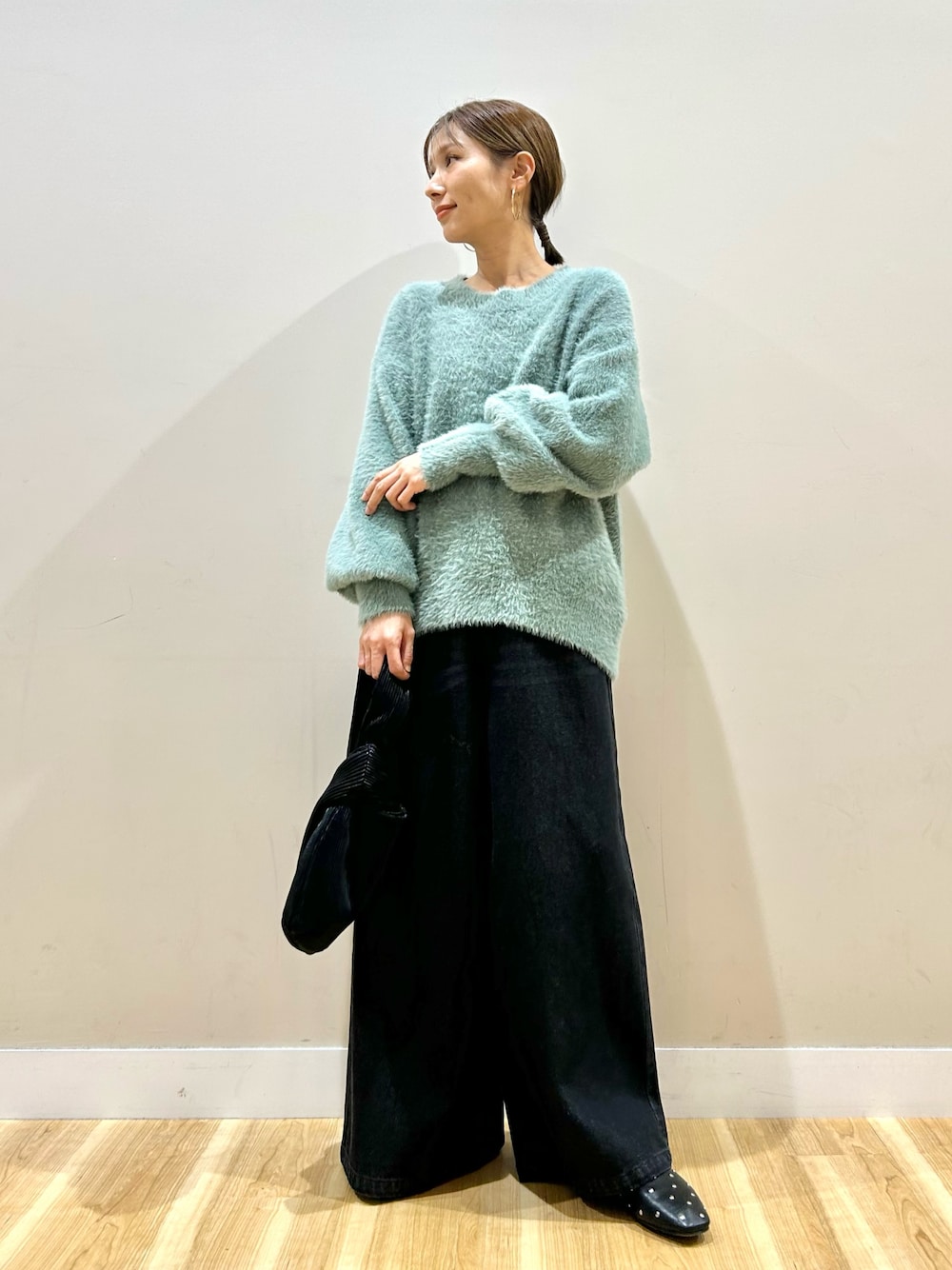 グリーン系のニット/セーター、ブラック系のデニムパンツを着用したレディースの冬コーディネートの1枚目の写真