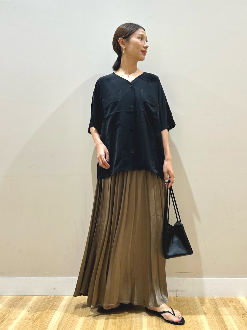 ブラック系のシャツ/ブラウス、ブラウン系のスカート、ブラック系のハンドバッグを着用したレディースの夏コーディネートの1枚目の写真