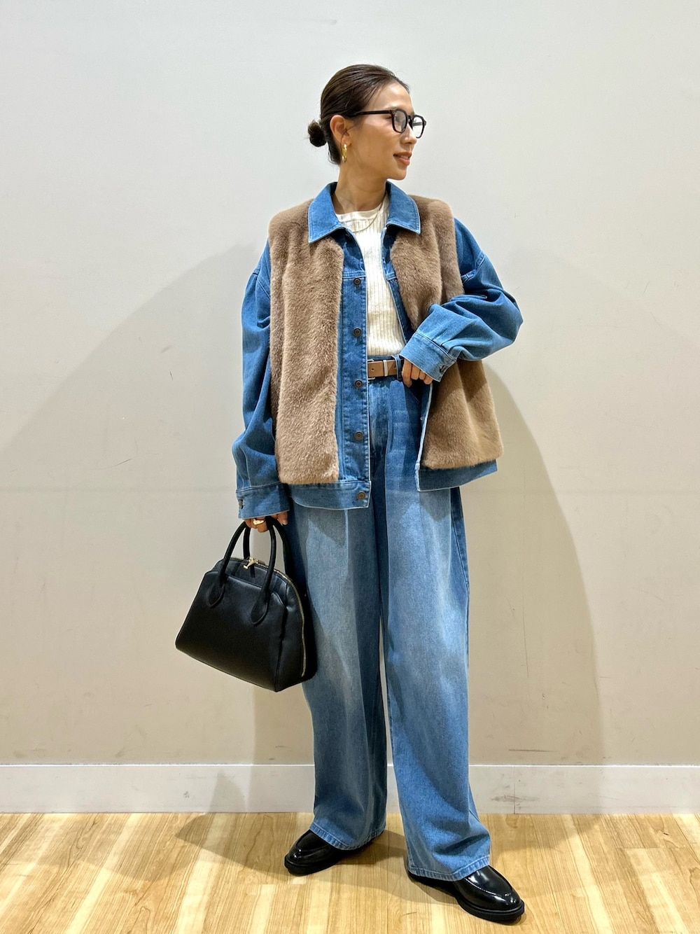 ブルー系のカバーオール、ブルー系のその他パンツ、ブラウン系のダウンベストを着用したレディースの秋コーディネートの1枚目の写真