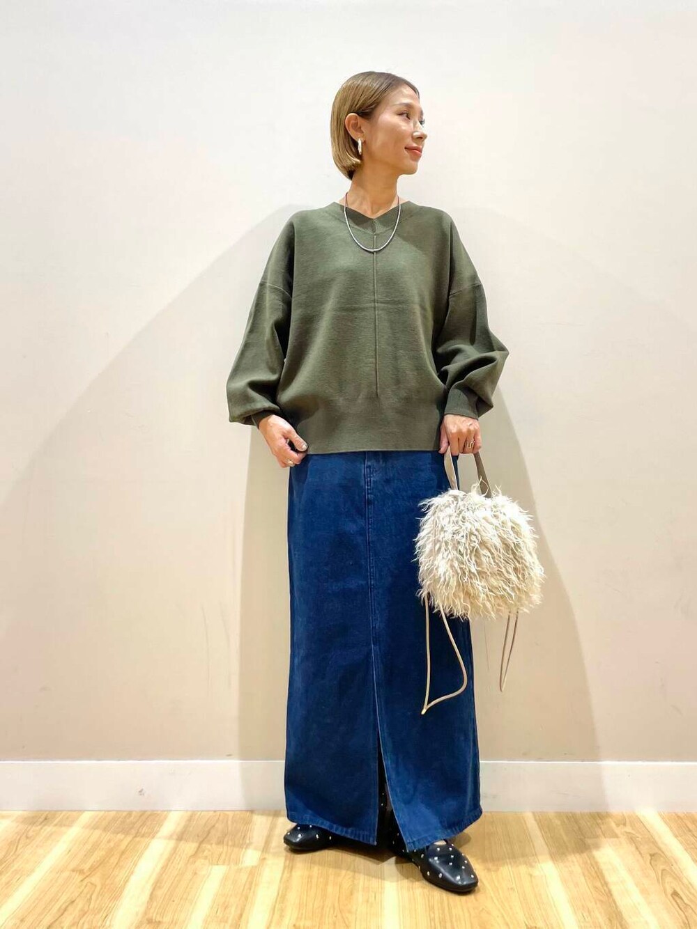 ベージュ系のショルダーバッグ、ブラック系のパンプス、ブルー系のスカートを着用したレディースの秋コーディネートの1枚目の写真