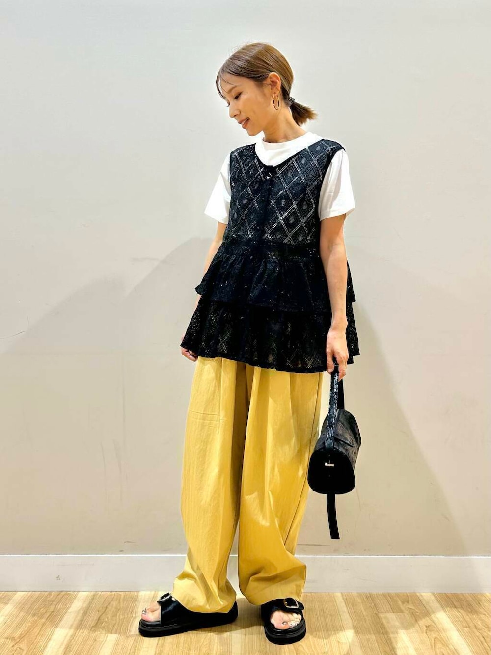 ブラック系のハンドバッグ、ベージュ系のその他パンツ、ホワイト系のTシャツ/カットソーを着用したレディースの夏コーディネートの1枚目の写真
