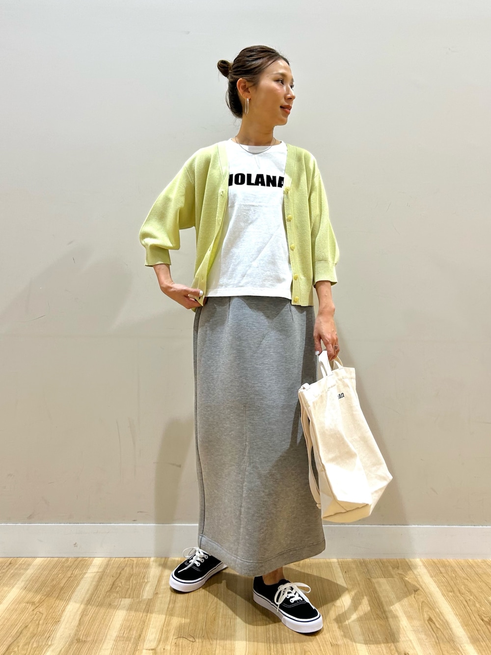 イエロー系のカーディガン/ボレロ、ホワイト系のTシャツ/カットソー、グレー系のスカートを着用したレディースの春コーディネートの1枚目の写真