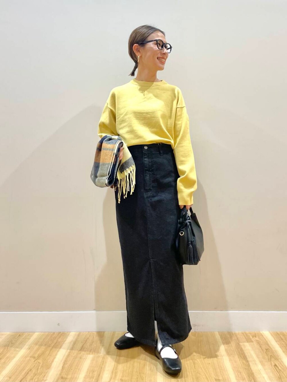 ブラック系のパンプス、ブラック系のスカート、グリーン系のショルダーバッグを着用したレディースの秋コーディネートの1枚目の写真