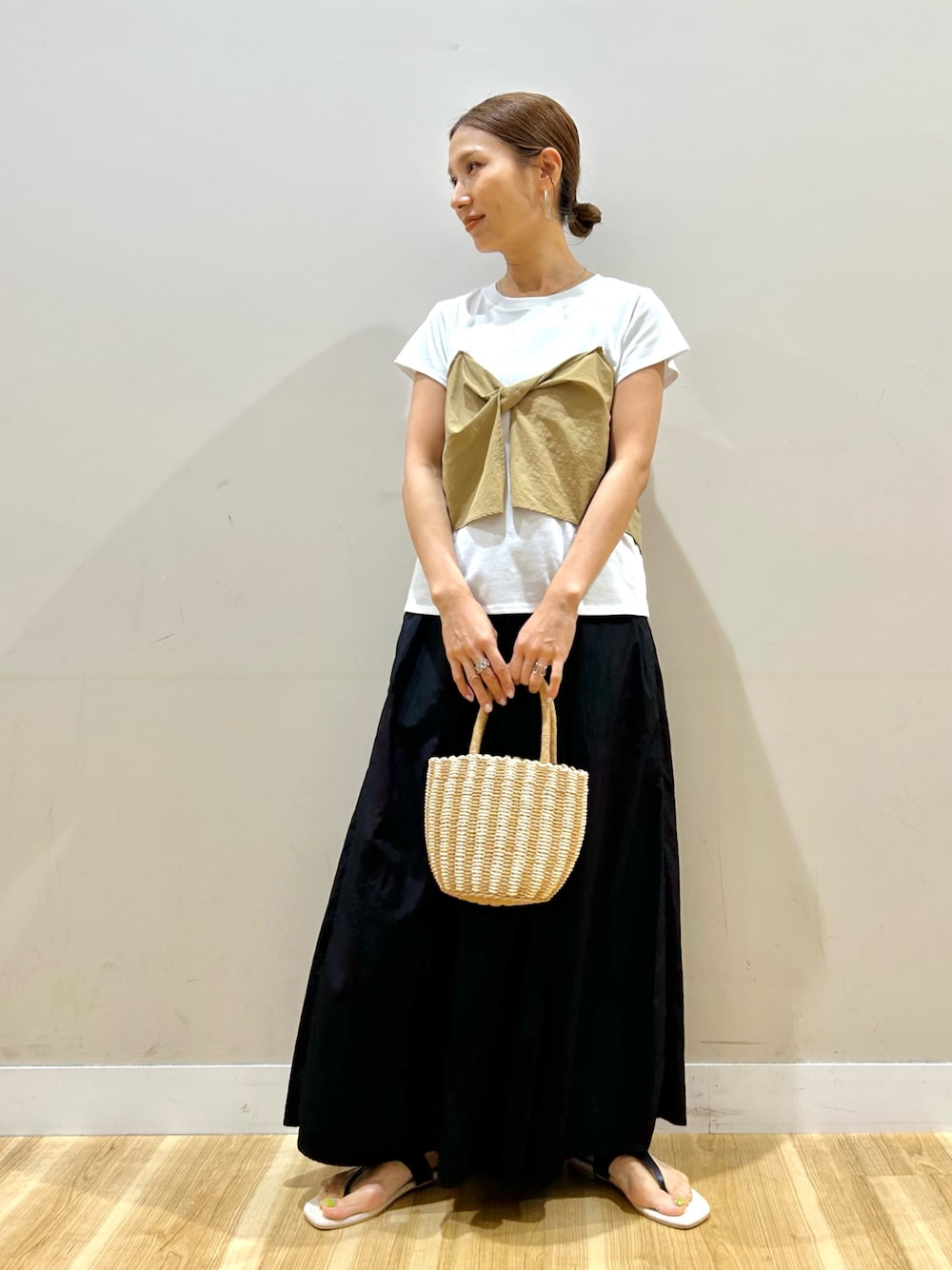 ベージュ系のTシャツ/カットソー、ブラック系のスカート、グレー系のハンドバッグを着用したレディースの夏コーディネートの1枚目の写真