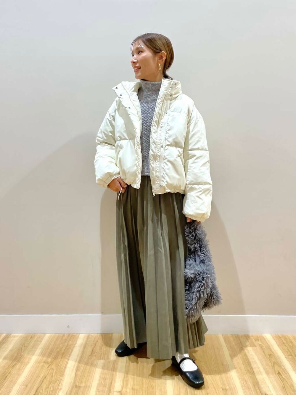 ブラック系のパンプス、グリーン系のスカート、グレー系のハンドバッグを着用したレディースの冬コーディネートの1枚目の写真