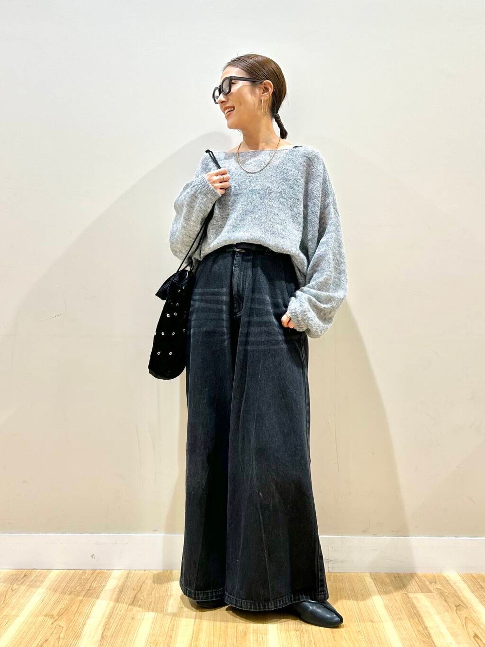 ブラック系のショルダーバッグ、ブラック系のデニムパンツ、グレー系のニット/セーターを着用したレディースの春コーディネートの1枚目の写真