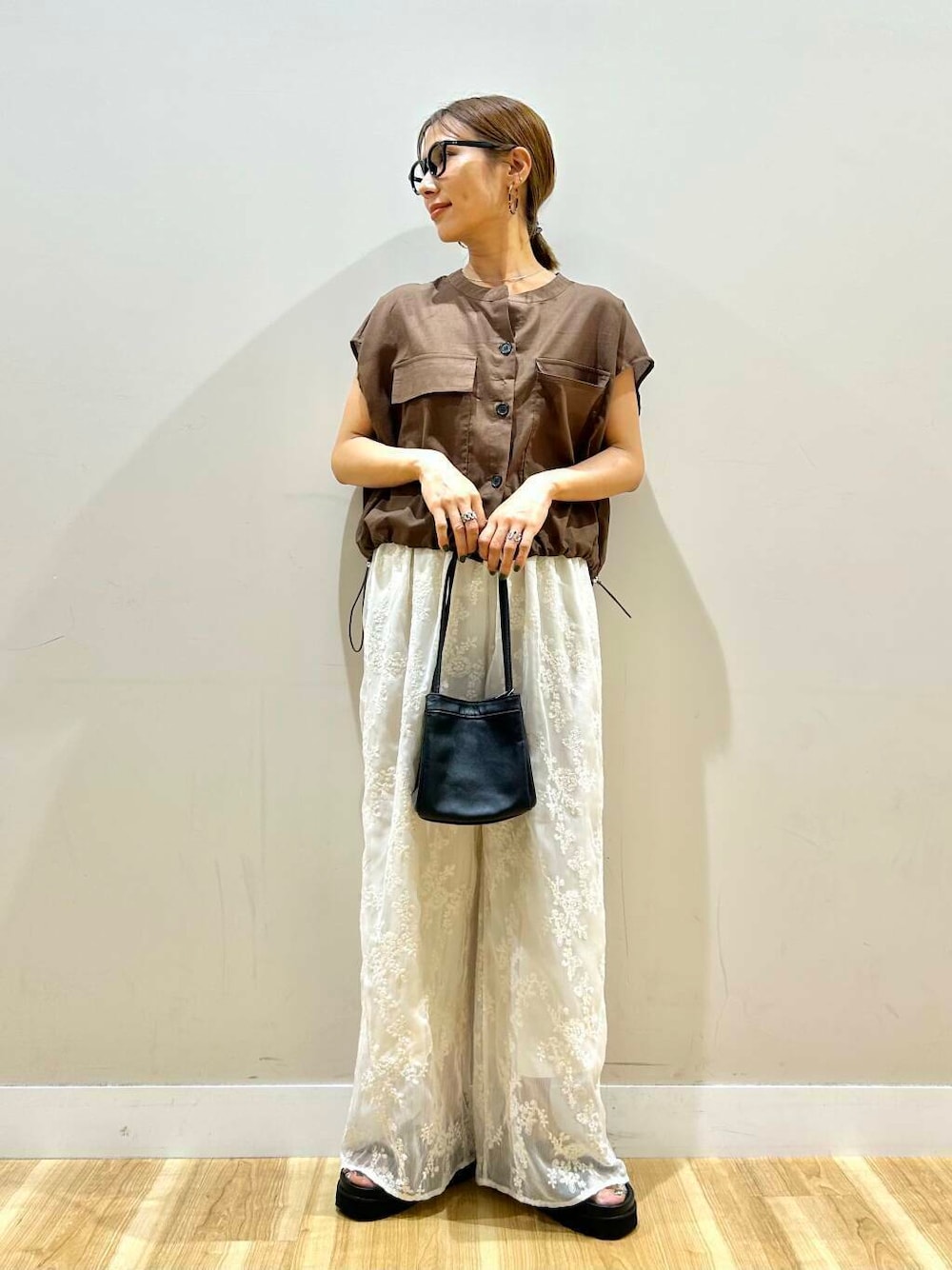 ホワイト系のその他パンツ、ブラック系のハンドバッグ、ブラック系のサンダルを着用したレディースの夏コーディネートの1枚目の写真
