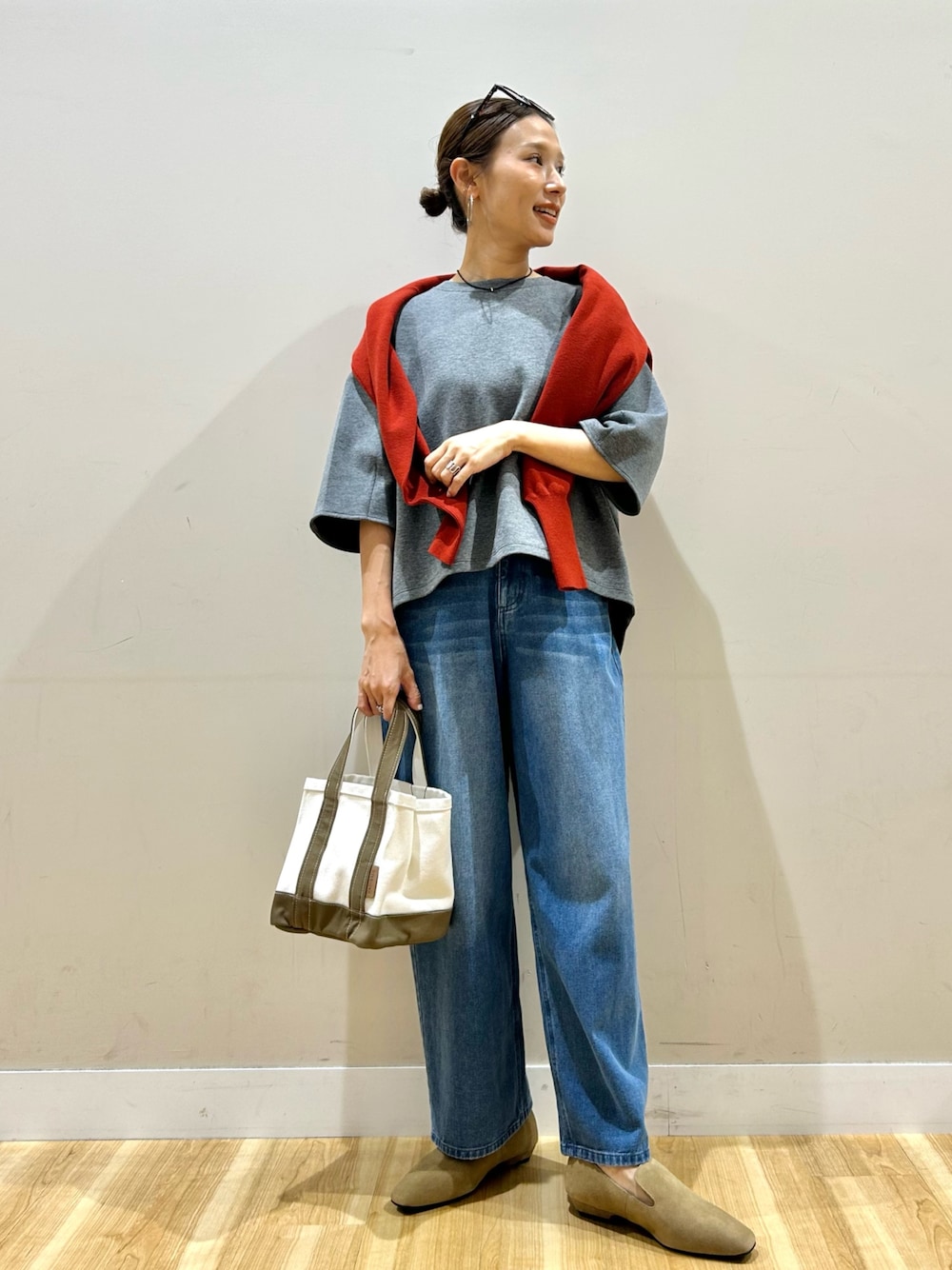 レッド系のニット/セーター、グレー系のTシャツ/カットソー、グレー系のトートバッグを着用したレディースの秋コーディネートの1枚目の写真