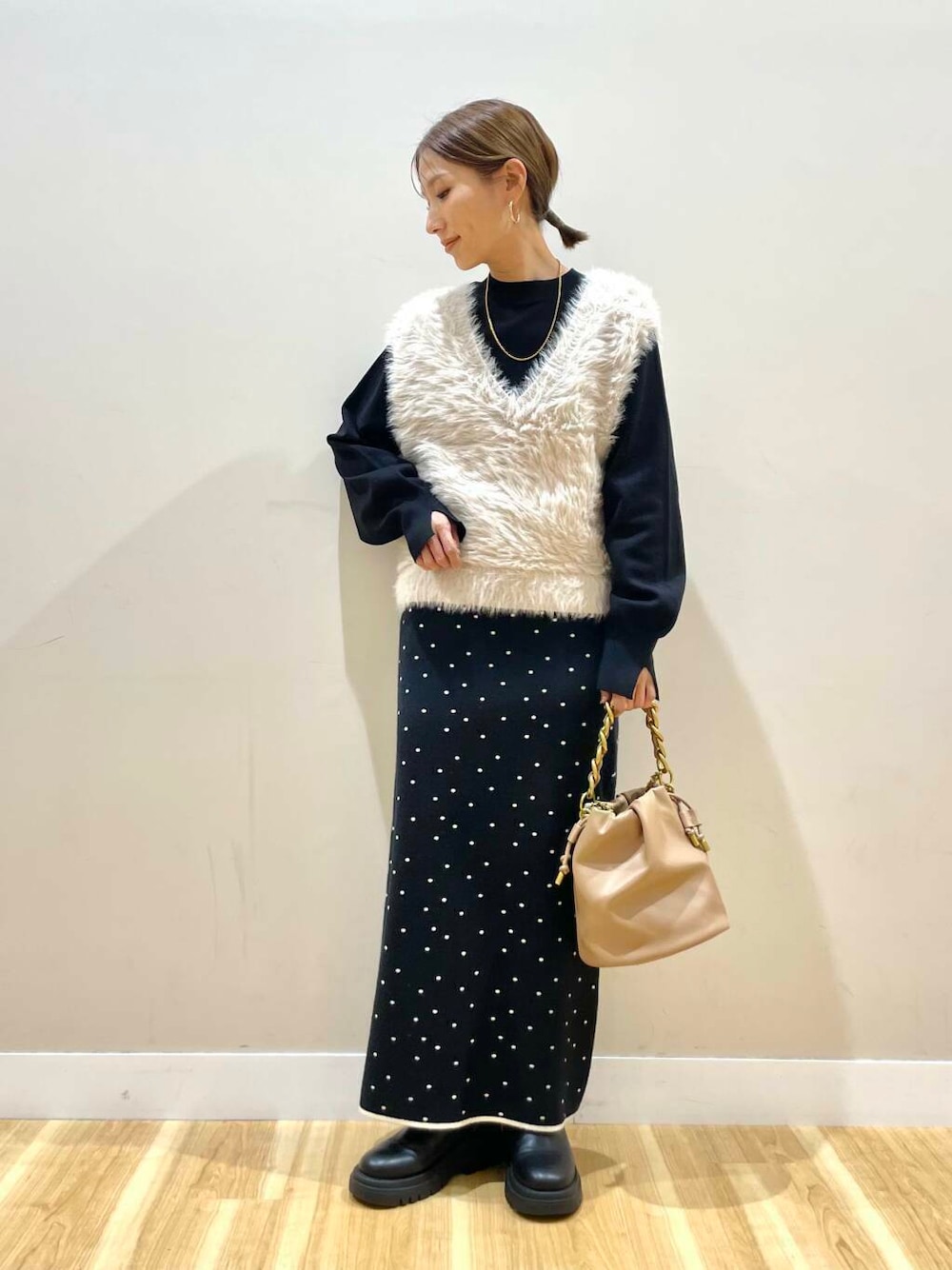 ブラウン系のショルダーバッグ、ブラック系のニット/セーター、ブラック系のスカートを着用したレディースの冬コーディネートの1枚目の写真