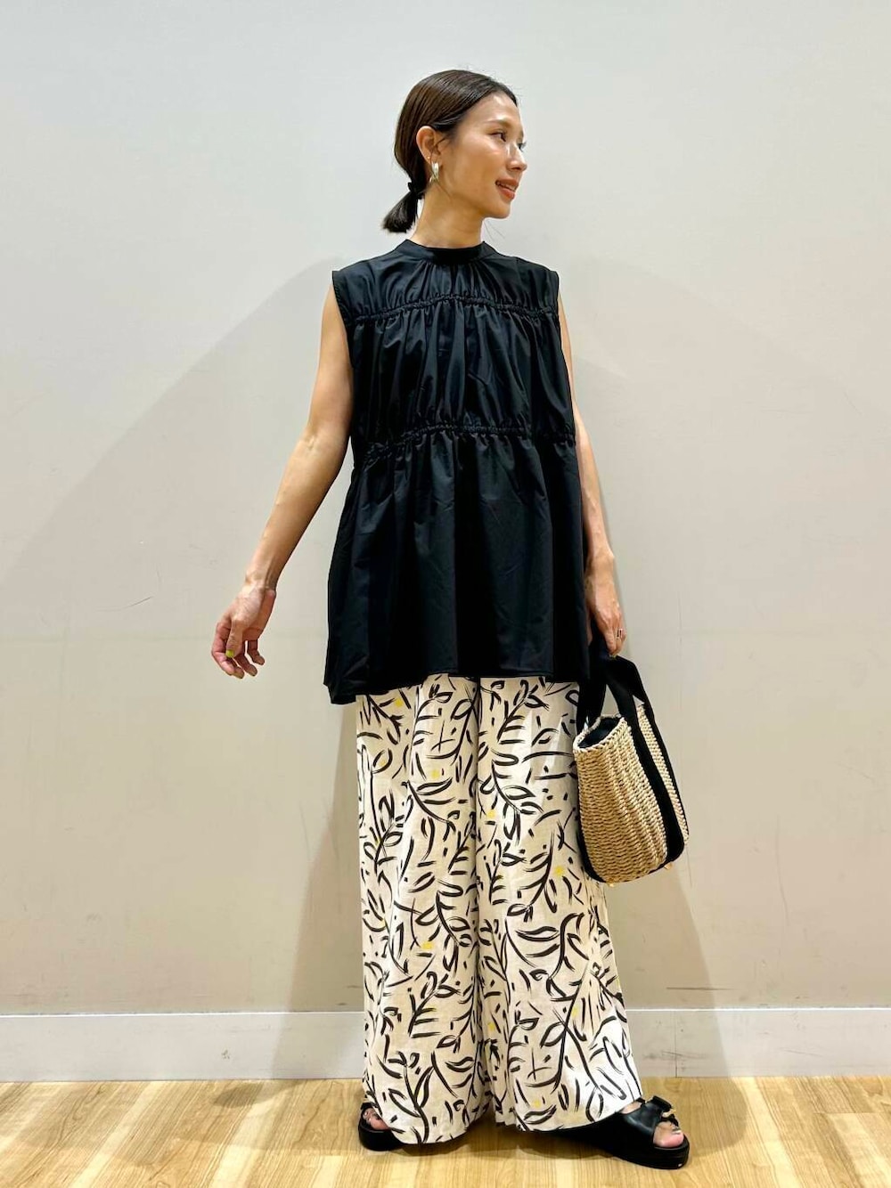 ホワイト系のその他パンツ、ベージュ系のハンドバッグ、ブラック系のサンダルを着用したレディースの夏コーディネートの1枚目の写真