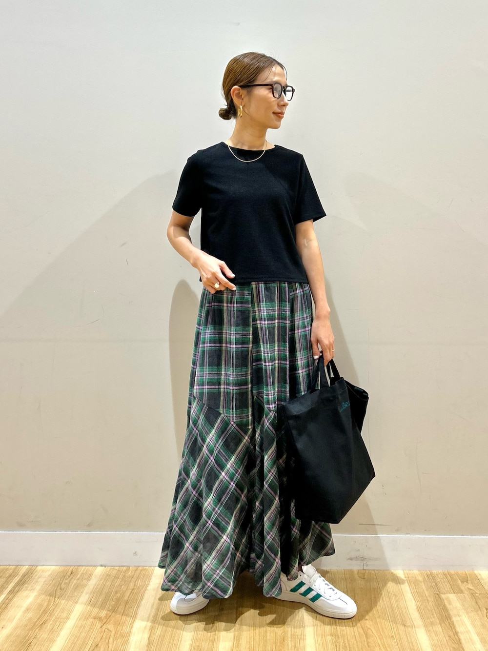 ブラック系のTシャツ/カットソー、グリーン系のスカート、ホワイト系のスニーカーを着用したレディースの夏コーディネートの1枚目の写真