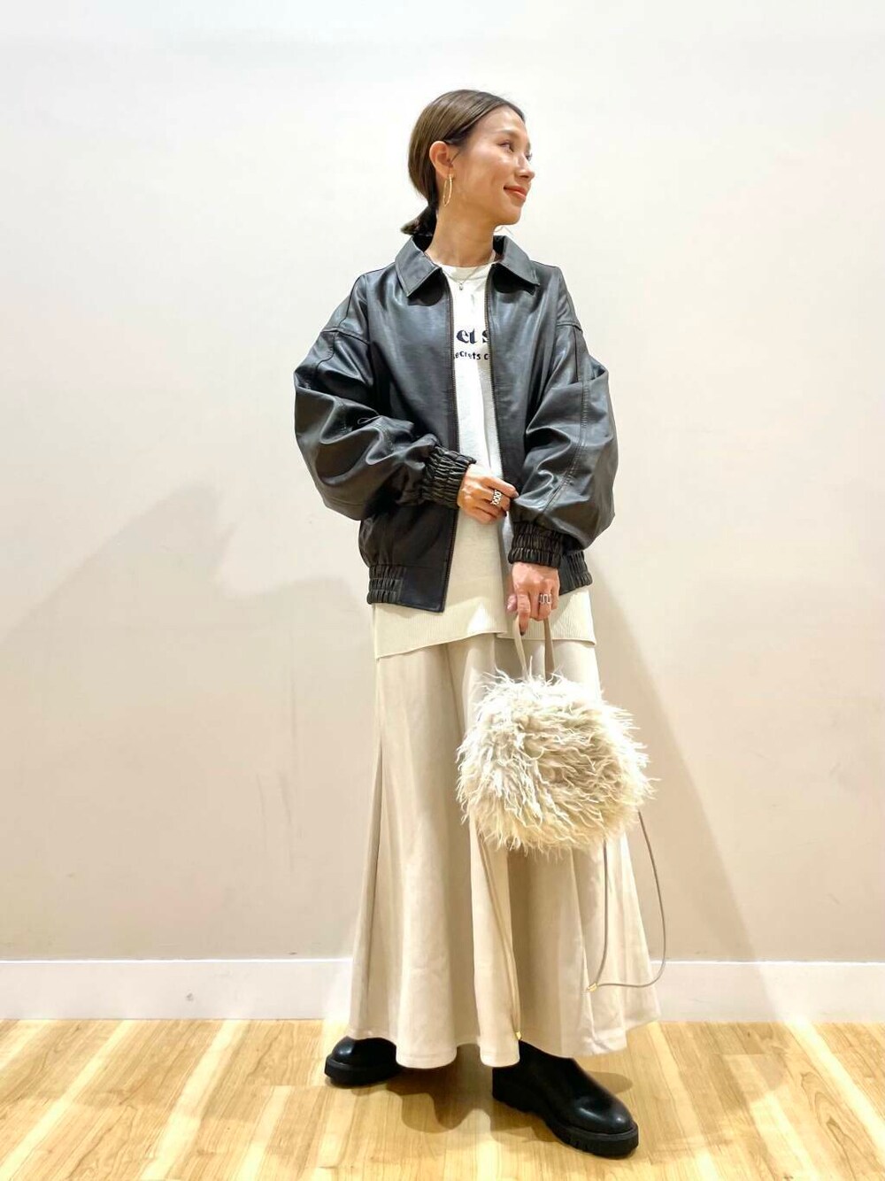 ブラック系のブーツ、ベージュ系のショルダーバッグ、ベージュ系のスカートを着用したレディースの秋コーディネートの1枚目の写真