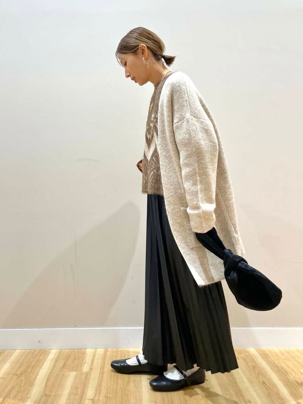 ブラック系のパンプス、ブラック系のハンドバッグ、ベージュ系のカーディガン/ボレロを着用したレディースの冬コーディネートの1枚目の写真