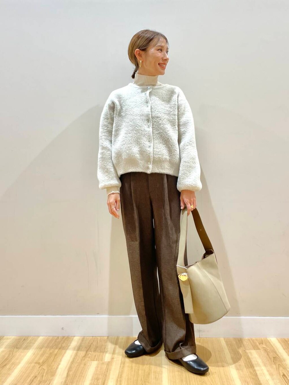 ブラック系のパンプス、ホワイト系のニット/セーター、ベージュ系のハンドバッグを着用したレディースの冬コーディネートの1枚目の写真