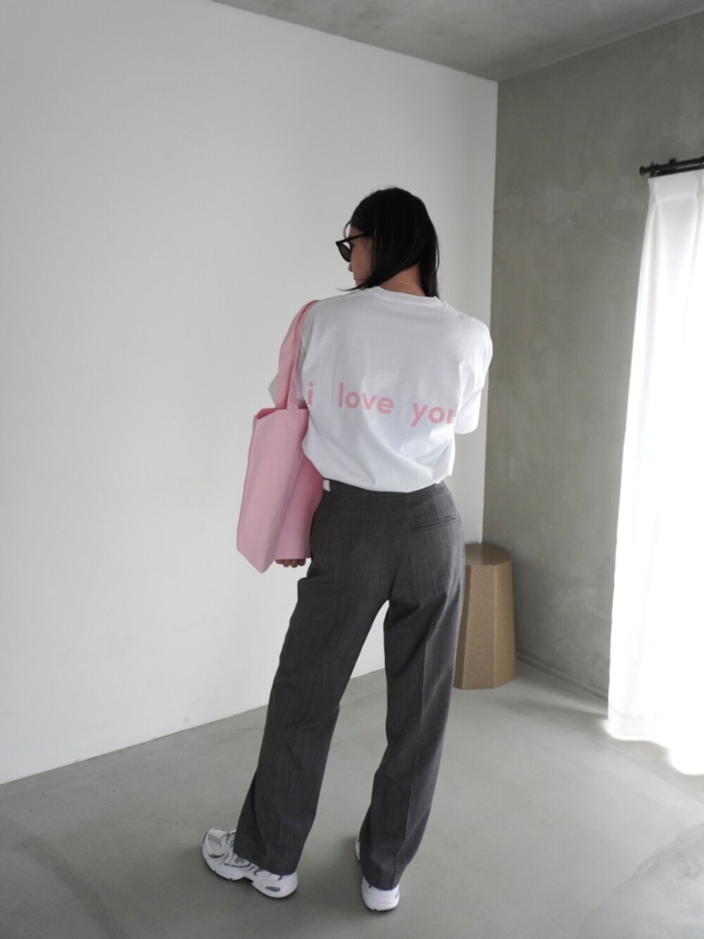 グレー系のスラックス、ピンク系のTシャツ/カットソー、ピンク系のエコバッグ/サブバッグを着用したレディースの春コーディネートの1枚目の写真