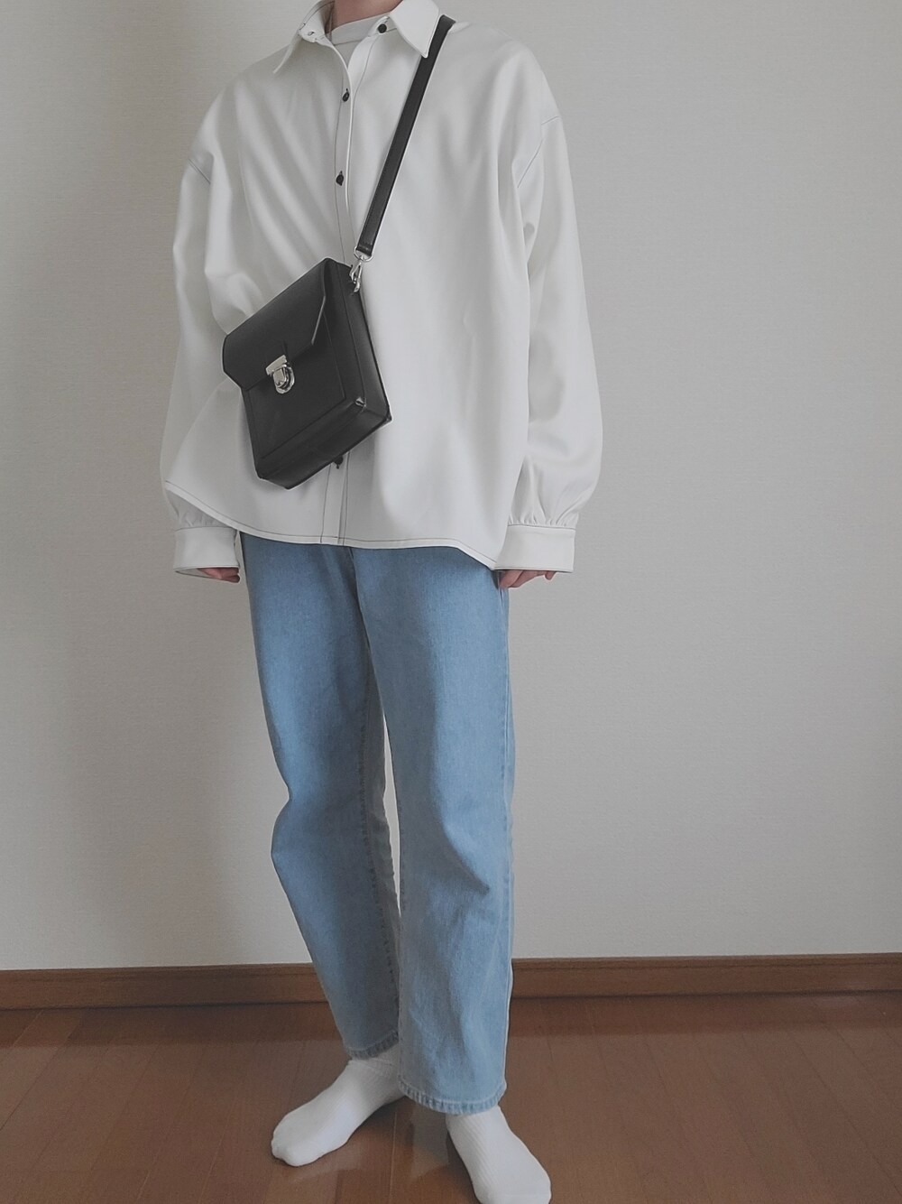 ブルー系のデニムパンツ、ブラック系のショルダーバッグ、ホワイト系のシャツ/ブラウスを着用したメンズの春コーディネートの1枚目の写真